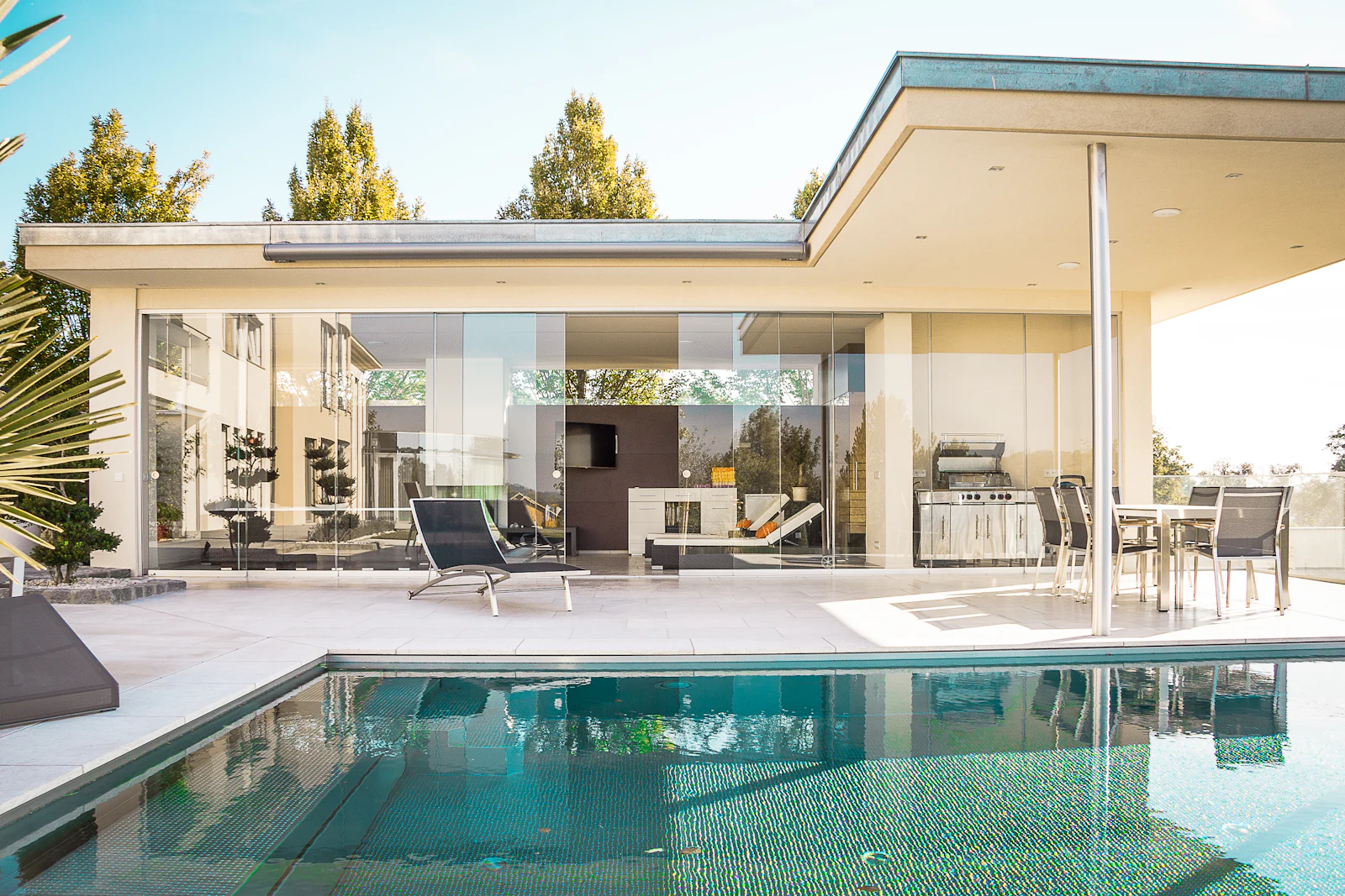 Wide view of a contemporary glass-walled home and its pool terrace